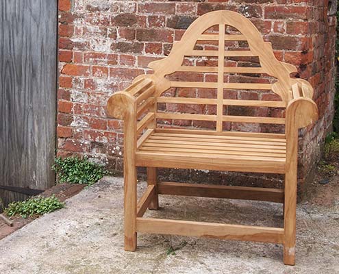 Wooden garden chair in front of brick wall