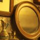 round antique mirror next to an ornamental jug and brass candle stick